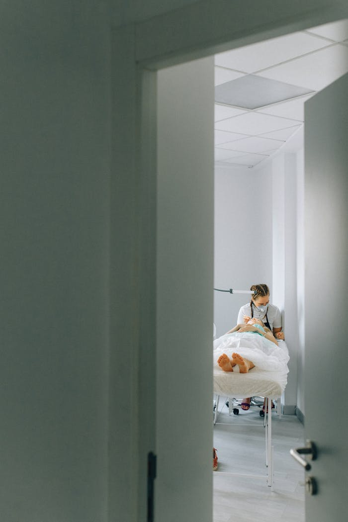 Open door view of a medical professional attending to a patient in a treatment room.