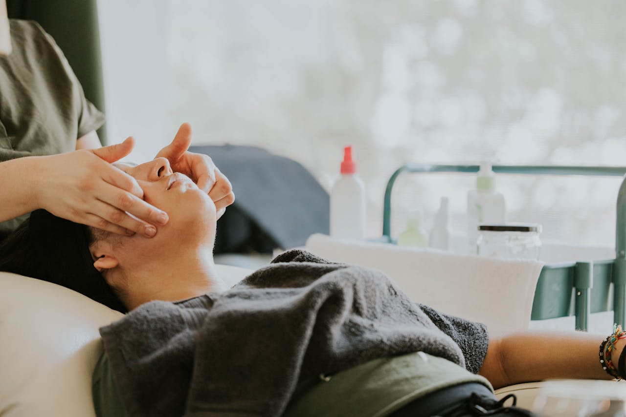 A peaceful setting of a woman receiving a facial massage in a spa environment.